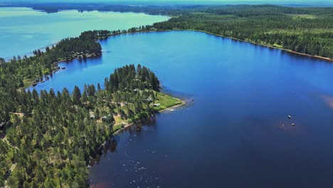 morning with beautiful fall landscape scenery of calm blue lake surrounded by lush pine tree forests in vansbro municipality, dalarna county, sweden - aerial drone