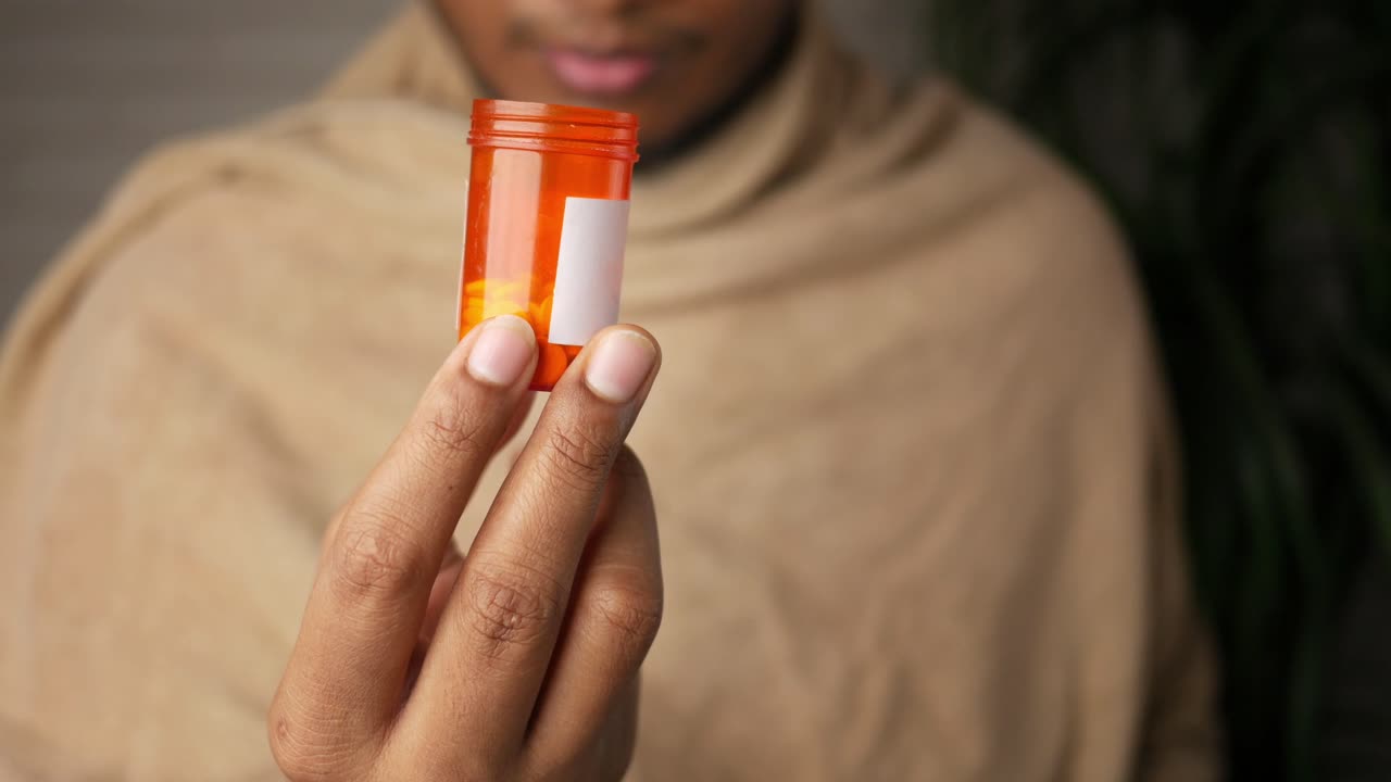 persona que sostiene un frasco de pastillas