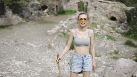 Portrait-of-beautiful-woman-with-wooden-stick-standing-in-front-of-sun-flare