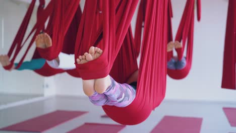las damas se acuestan con los pies descalzos en largas hamacas de yoga aéreas