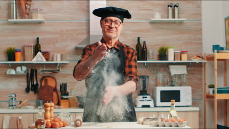 sentado en la mesa de la cocina ang aplaudiendo con las manos wuth harina