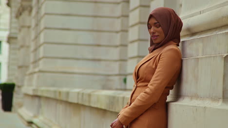 portrait of muslim businesswoman wearing hijab and modern business suit standing outside city office buildings