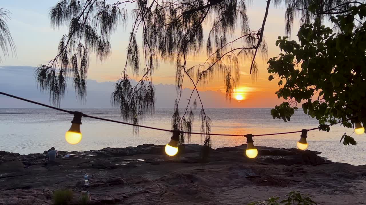 String lights illuminate Fijian beach at sunset, serene and picturesque