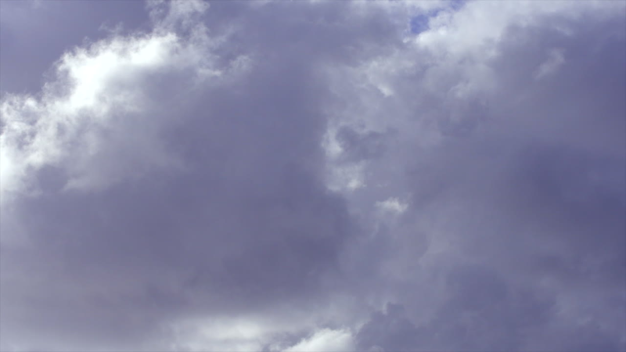 Time lapse: Bright white clouds moving and changing shape across the blue sky