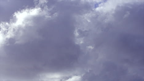 time lapse: bright white clouds moving and changing shape across the blue sky
