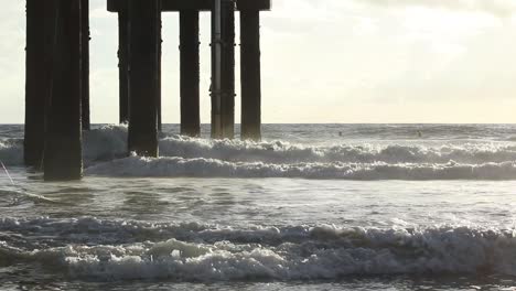 waves crashing on a pier in slow motion during sunrise