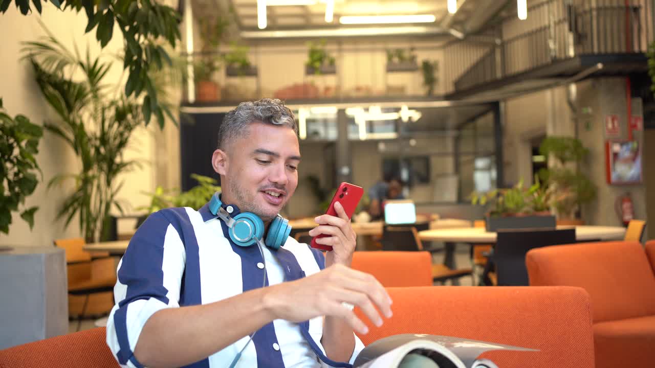 Man reading magazine while having phone call in office
