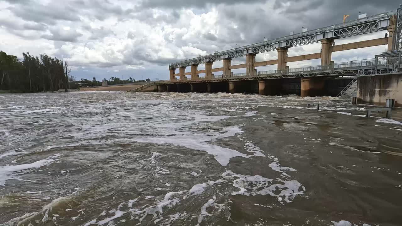 View across the swollen and swiftly flowing Murray River at the Yarrawonga weir bridge during flooding conditions