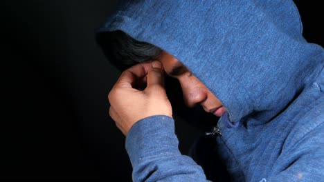 hombre con capucha con la cabeza en las manos