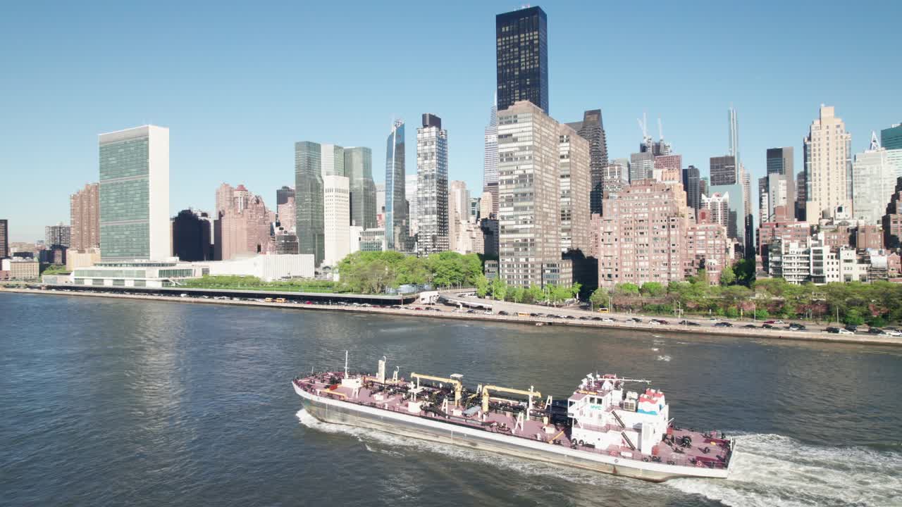 Industrial-looking ship on New York's East River, United Nations Headquarters and Midtown Manhattan in background