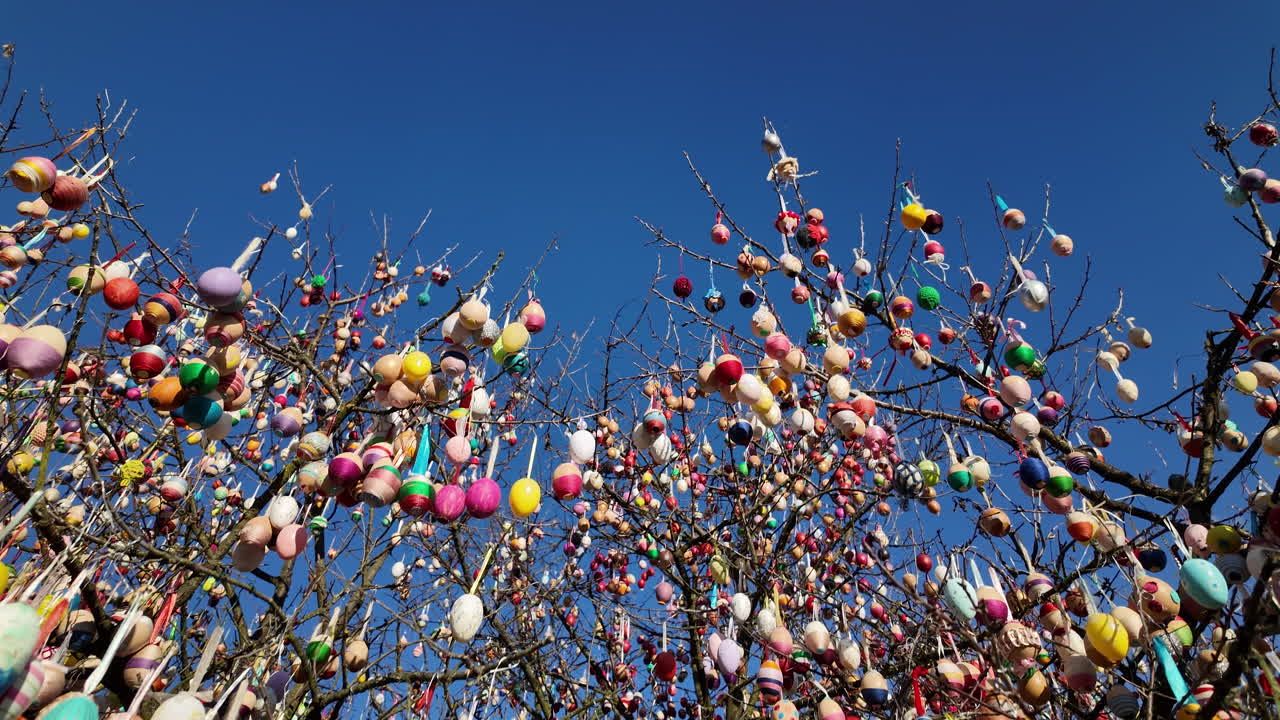 Easter egg tree with colorful decorations against blue sky
