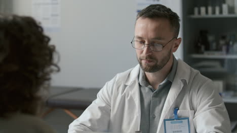 doctor taking medical records and talking to female patient on consultation