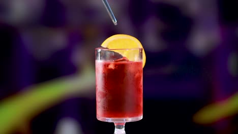 a negroni cocktail is garnished with an orange slice in a dimly lit bar setting, highlighting vibrant colors and a relaxed atmosphere