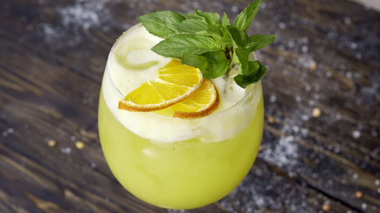 Et glas gul lemonade med mynte på en træoverflade