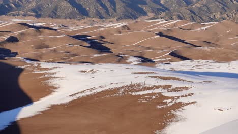 Tilting-gimbal-shot-of-sand-dunes-and-mountains