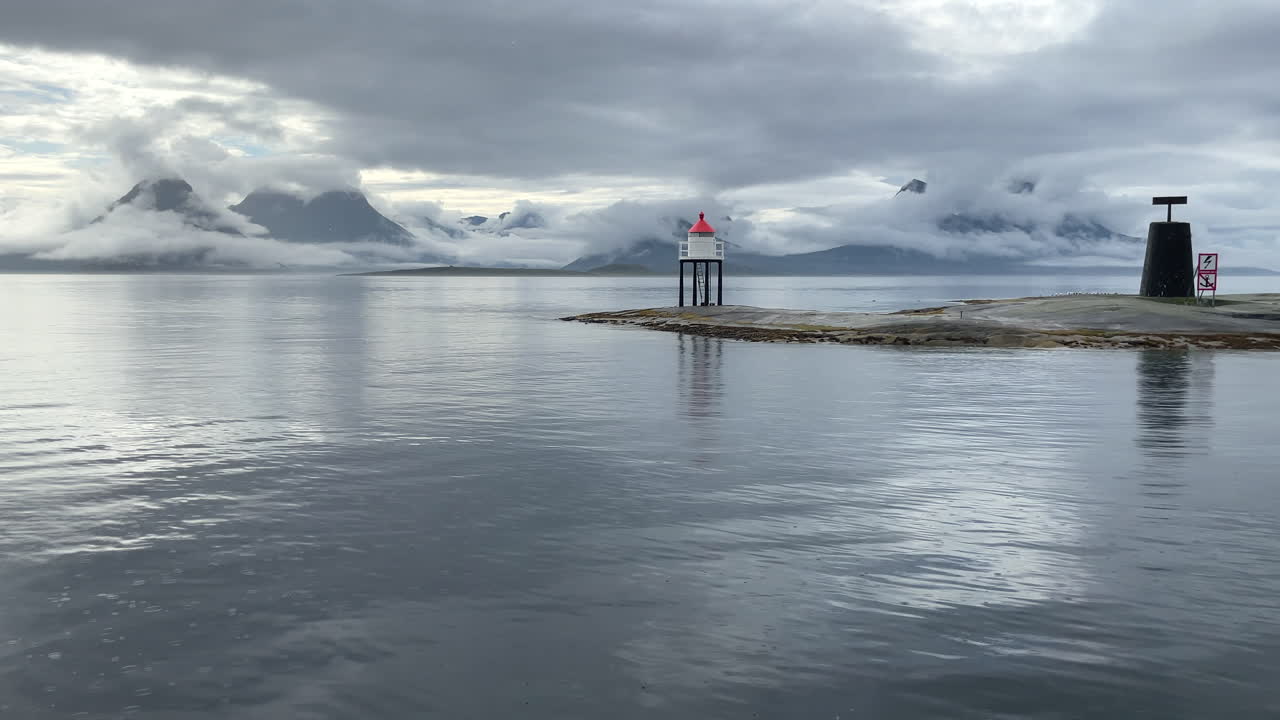 дождь льется на поверхность океана в угрюмый летний день, облака окружают горы на побережье гельголанда в нордланде