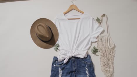 Video-of-white-t-shirt,-denim-shorts,-hat,-bag-and-copy-space-on-white-background