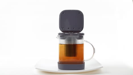 stream of hot water pouring into a tea infuser inside a glass mug with a dark background