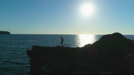 viajero masculino anónimo con dron volador en la costa rocosa del mar