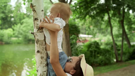 hermana sosteniendo al hermano pequeño en las manos al aire libre. familia pasando el tiempo en el parque