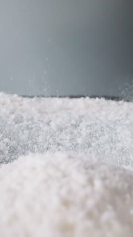 pile of white starch bounces and spills into shaken vessel. finely ground foodstuff moves up and down. movement of powdered ingredient for cooking macro