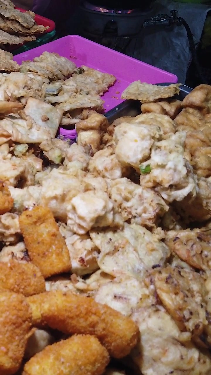 Gorengan indonesiani (frittelle fritte), primo piano verticale da smartphone, esposizione di cibo in un mercato notturno di strada.