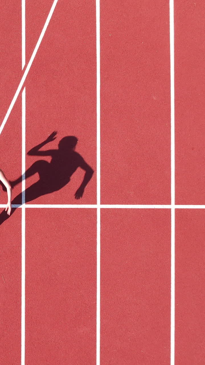 Top down vertical view of a female athletes shadow at the starting line ...