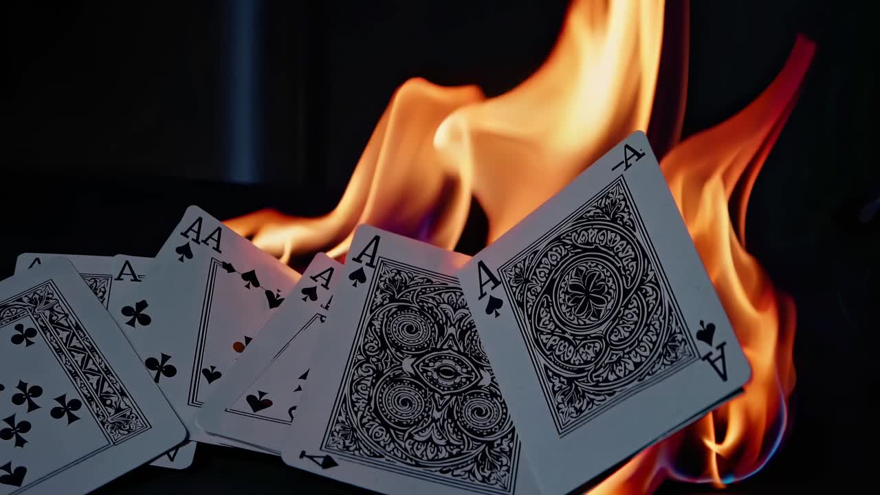 Close-up shot of playing cards with flames in the background, creating a dramatic and intense video