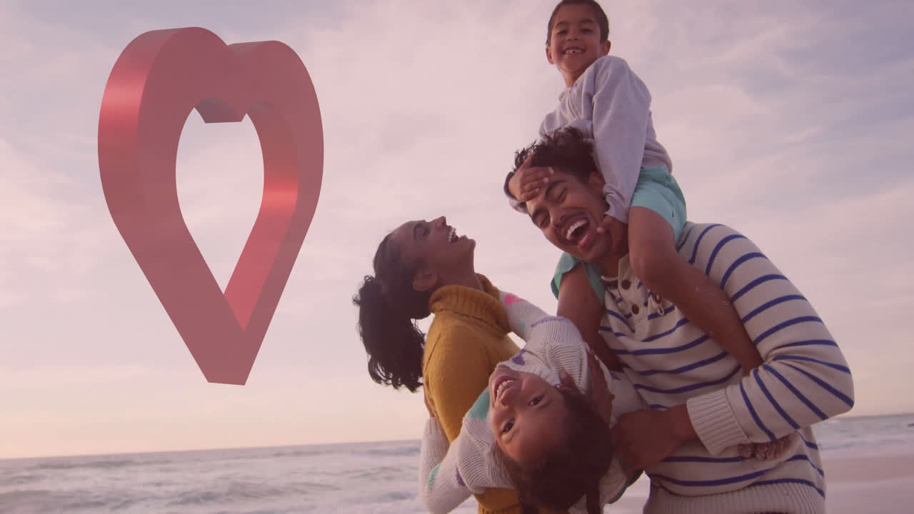 At beach, family playing together with heart-shaped animation in sky above
