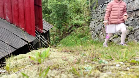 young girl wearing pink is cuddling with her cat - cute handheld everyday outdoor shot - low angle with cat and girl walking against camera and out of frame