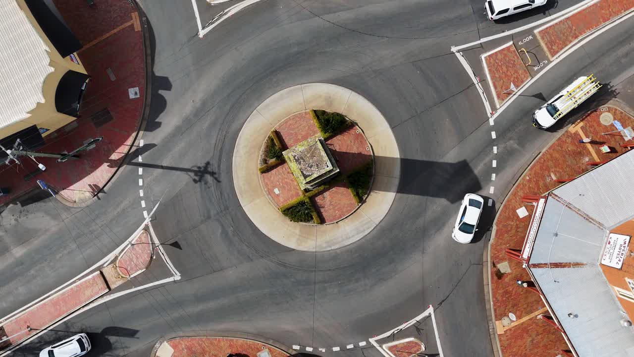 Overhead drone footage captures cars and trucks moving through a sunlit roundabout in Coonabarabran, New South Wales, with clear shadows and steady camera