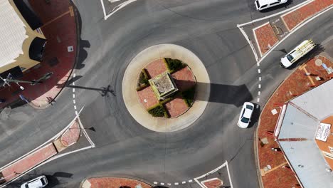overhead drone footage captures cars and trucks moving through a sunlit roundabout in coonabarabran, new south wales, with clear shadows and steady camera