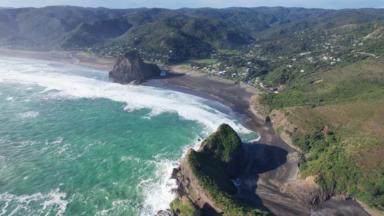 olas chocando en la playa de piha con lion rock y taitomo rock en la región de auckland, isla del norte, nueva zelanda