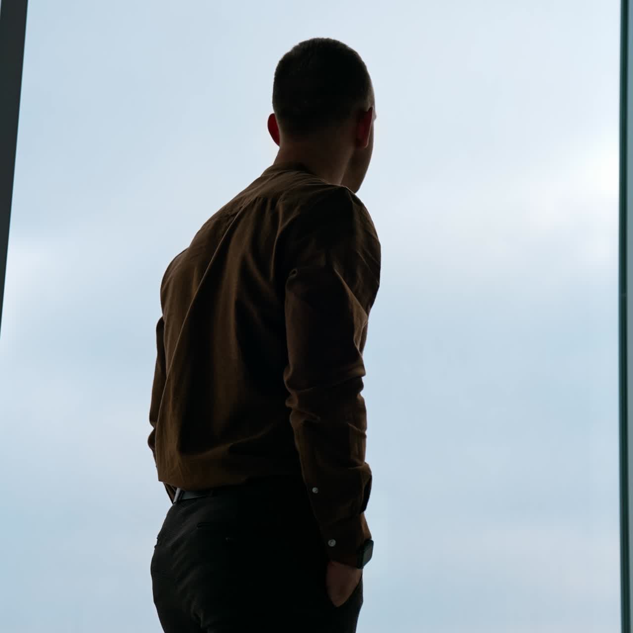 A businessman looks out the window in a contemplative way