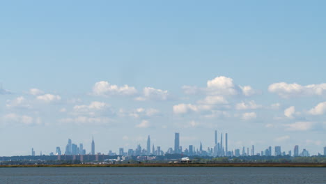 commercial jet crosses frame against clear blue sky as camera tilts down to new york city skyline on horizon