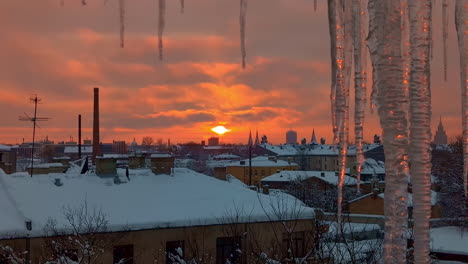 Naranja,-Brillante-Puesta-De-Sol-Sobre-Un-Pueblo-Nevado-En-Invierno-Con-Carámbanos-En-Primer-Plano