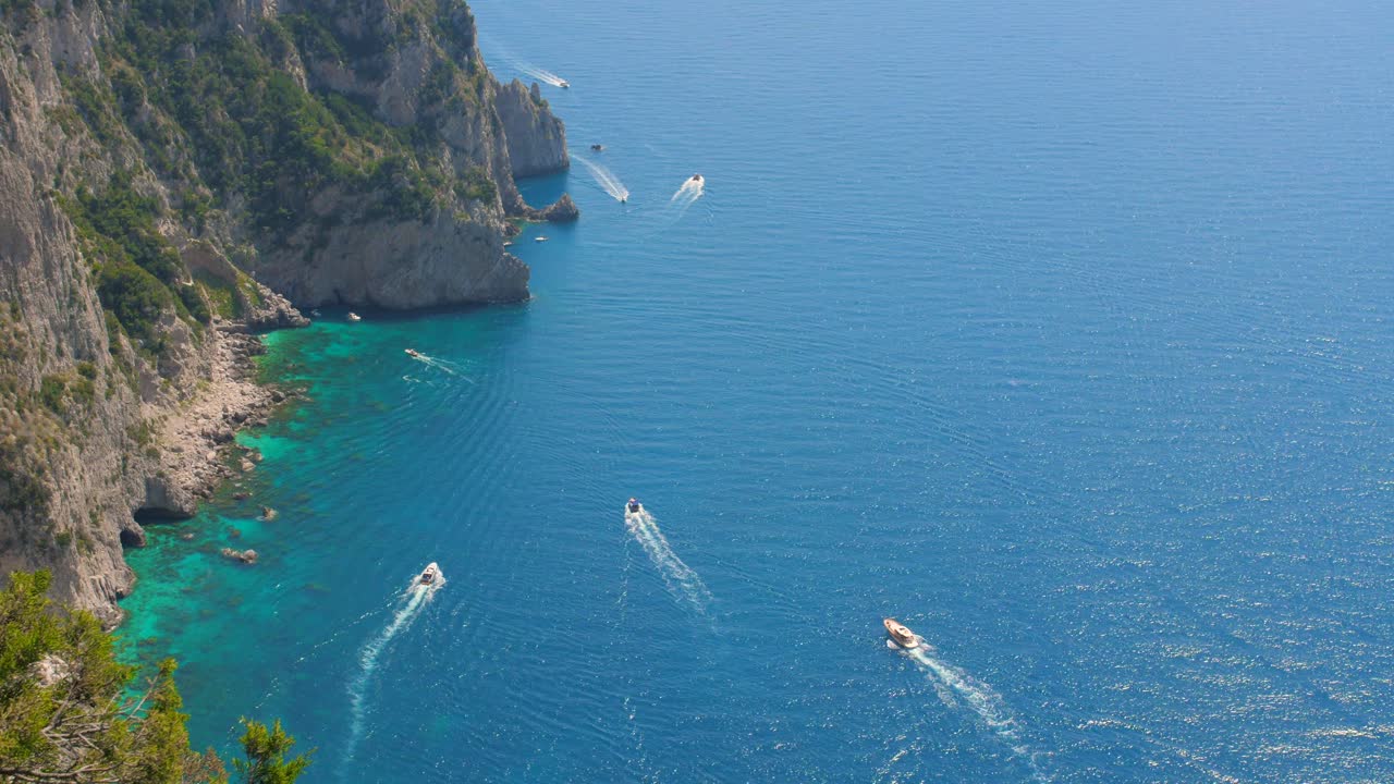 disparo cinematográfico de alto ángulo sobre barcos a motor que navegan en las cristalinas aguas azules del mar tirreno, isla de capri, italia durante el día