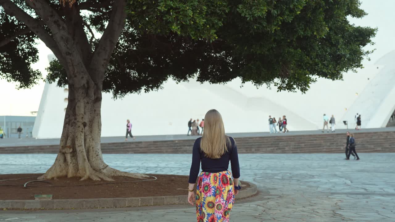 Ujęcie od tyłu blondynki w kwiecistej spódnicy idącej w Santa Cruz de Tenerife.
