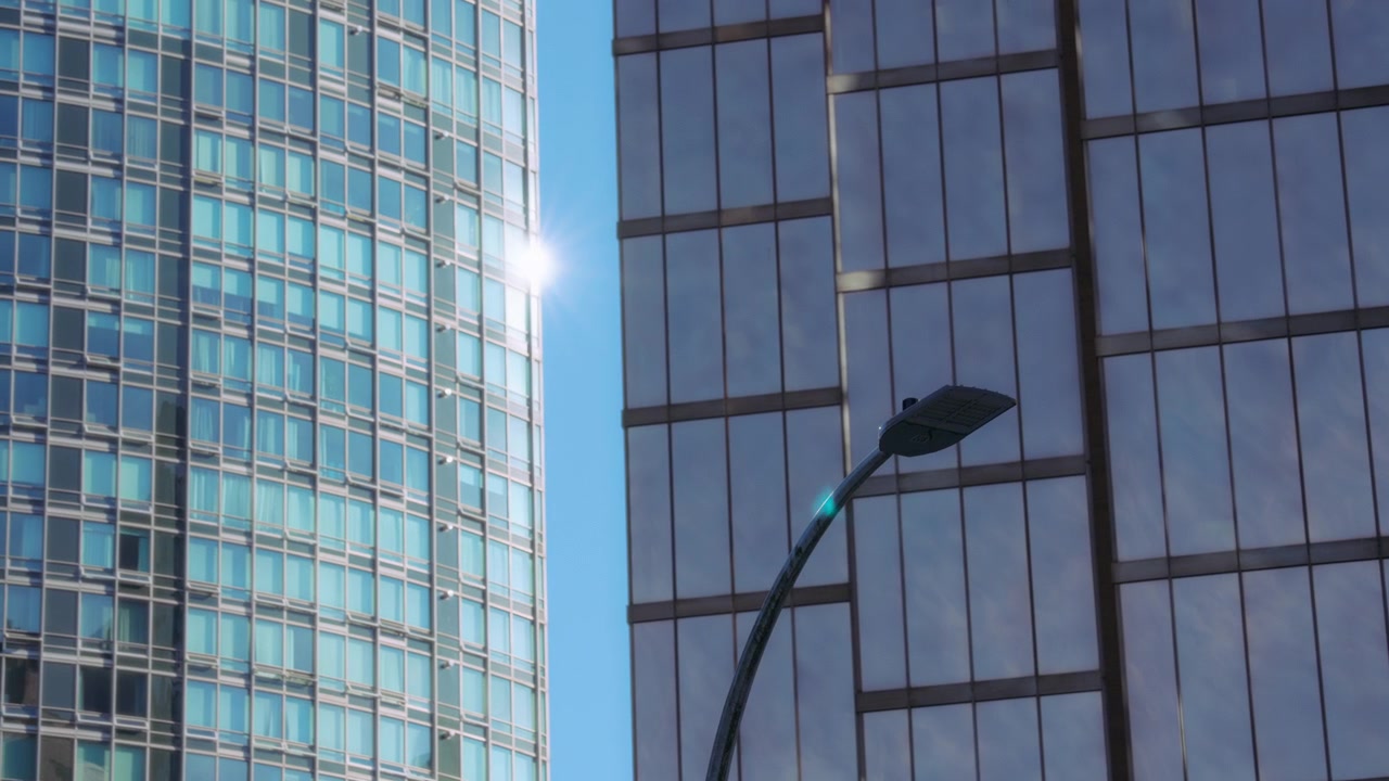 Sol brilhando atrás de prédio alto de vidro