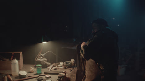 a bombmaker assembles a bomb in his workshop at night