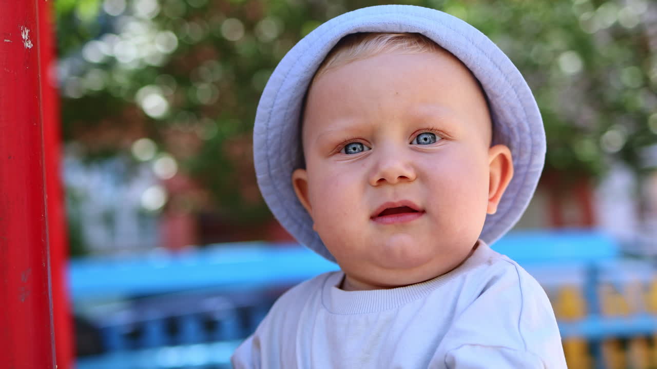 Un bambino con gli occhi azzurri, con un cappello di Panama in testa, gioca nella sabbia. I bambini giocano in una giornata di sole all'aperto con la sabbia.