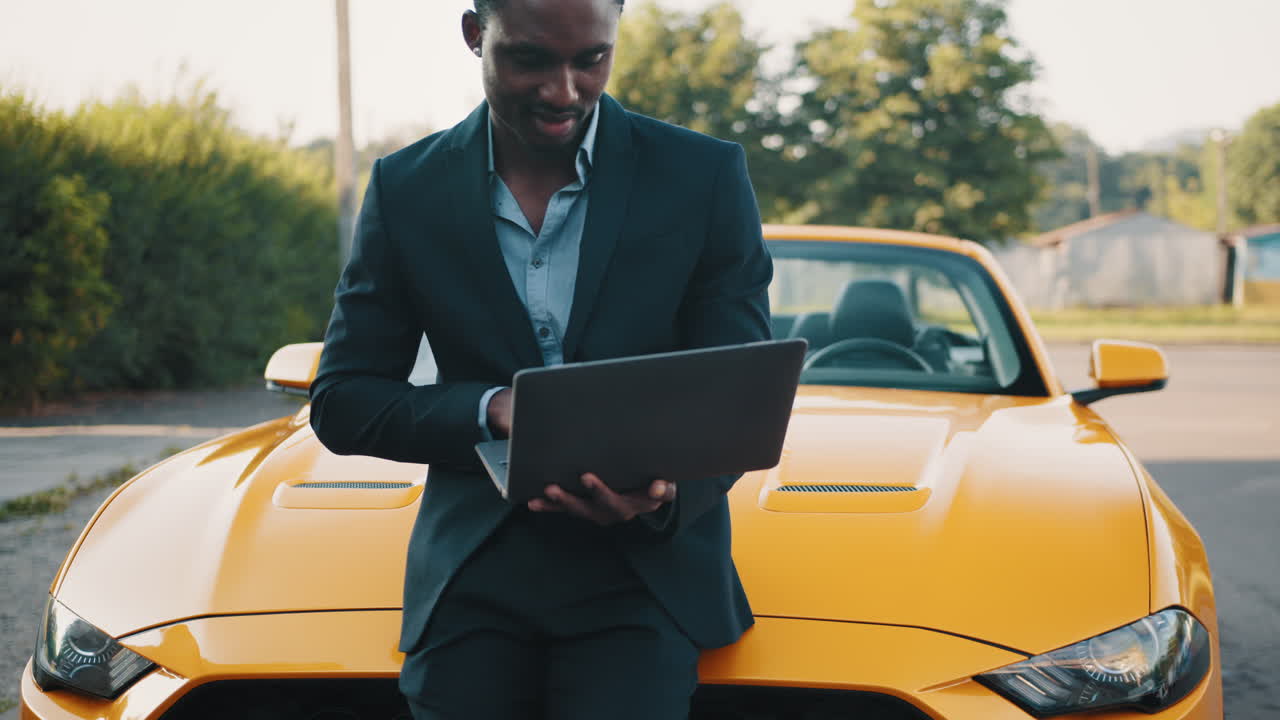 hombre de negocios usando una computadora portátil cerca de un coche amarillo