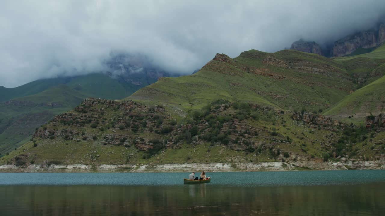 산의 호수 에서 카누 를 타고 있는 부부