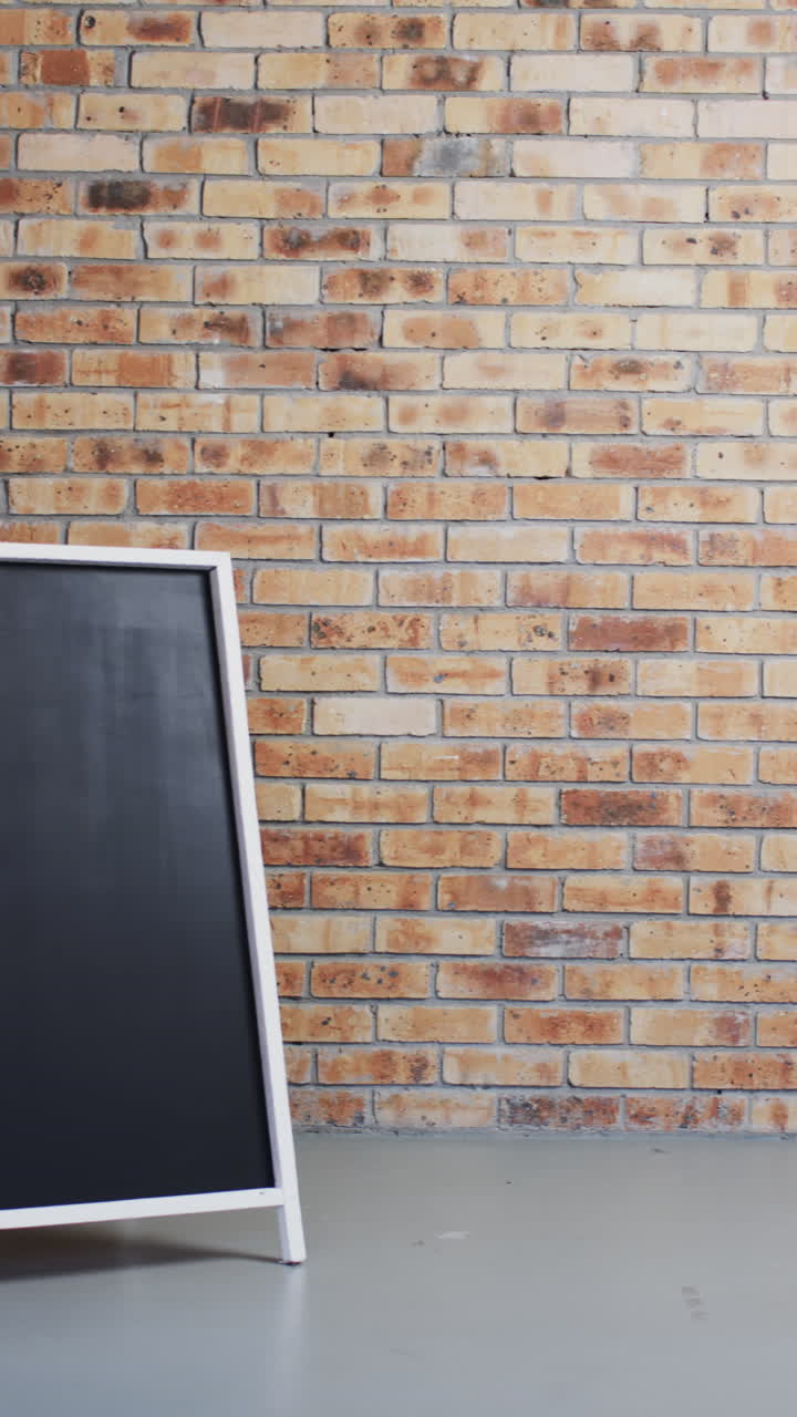 Vertical video of blackboard sign with copy space on white stand and brick wall background