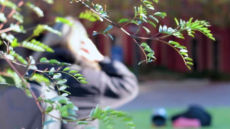 person outdoors, obscured by foliage, adjusting something