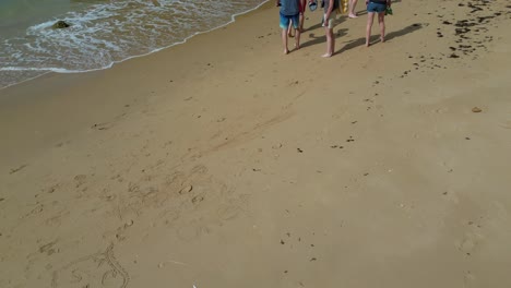 Eine-Gruppe-Von-Menschen-Läuft-An-Einem-Sandstrand-Entlang,-Wo-Die-Wellen-Brechen