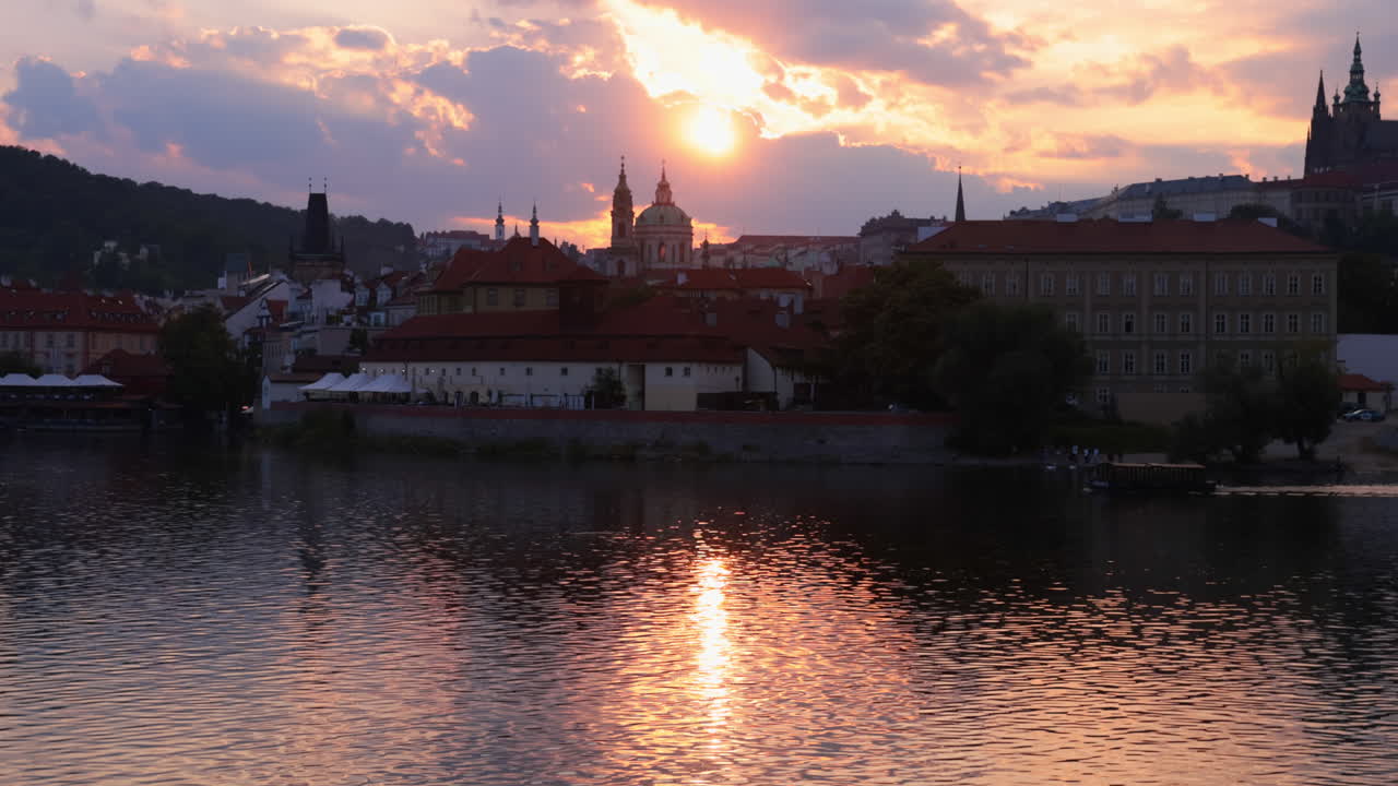 Passare attraverso i rami degli alberi per rivelare la Chiesa di San Nicola e il fiume Moldava al tramonto, Repubblica Ceca