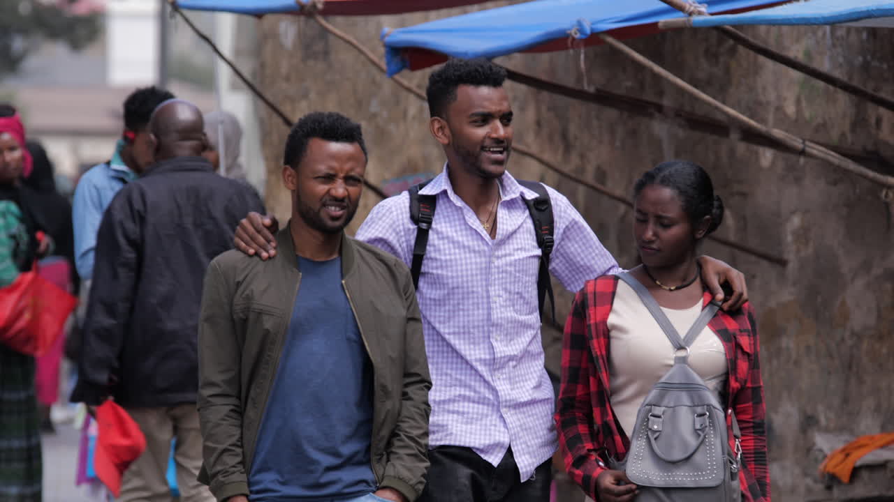 Young friends walk and chat on a sidewalk in Addis Ababa, Ethiopia
