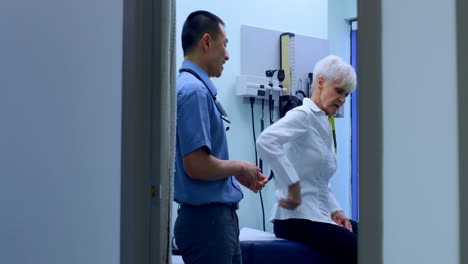 joven médico asiático examinando a un paciente anciano en la clínica 4k