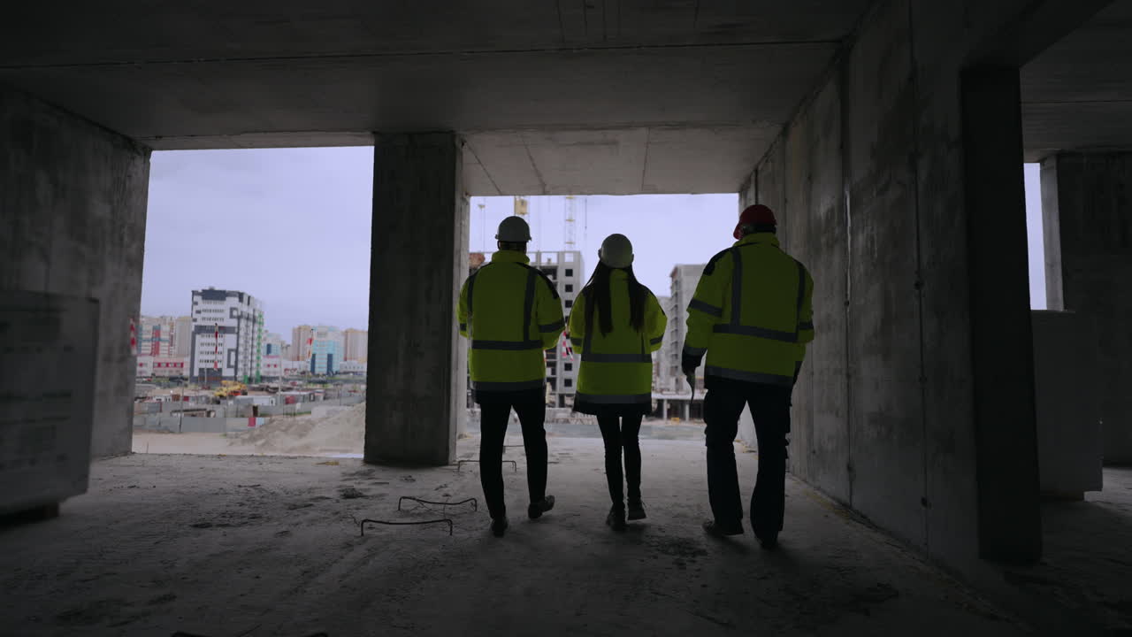 los ingenieros civiles están caminando en el edificio bajo construcción vista trasera de las constructoras profesionales femeninas y masculinas